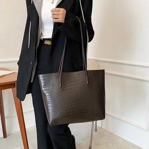 Detail of deep brown crocodile pattern tote bag with spacious interior and slim straps