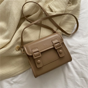 Détail d'un petit sac bandoulière vintage marron sur des tricots d'automne doux