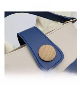 Macro detail of the navy blue and cream leather patchwork bag with a wooden buckle
