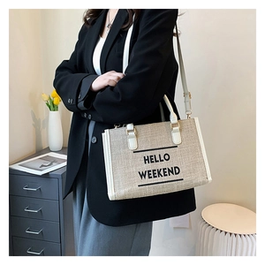 Canvas tote bag detail showing beige linen texture and HELLO WEEKEND lettering