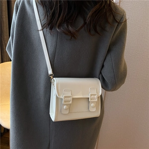 Petit sac à bandoulière blanc crème minimaliste porté à l'épaule, vue sur la taille