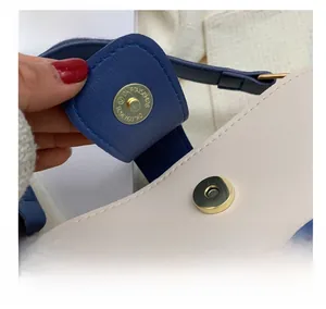 Close-up of golden magnetic snap button and lychee grain leather on blue contrast bag