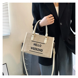 Detail showing the textured beige canvas material and Hello Weekend print on the tote bag