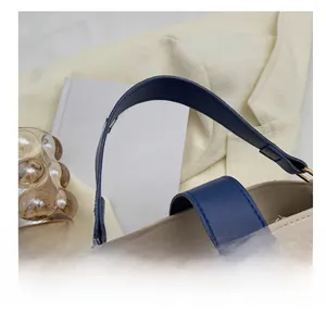 Detail of beige leather handbag with blue handles and circular wooden buckle accent