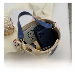 Detail view of contrast color cylinder bag showing internal capacity with daily items