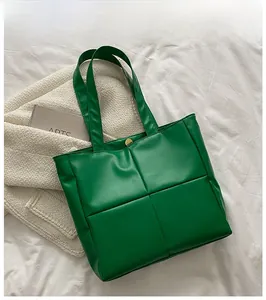 Detail of green quilted tote bag showing large square stitching and golden magnetic clasp