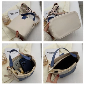 Detail view of contrast color bucket bag with wide printed strap and inner storage