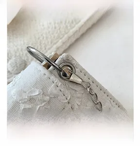 Detailed close-up of the silver metal ring hook and embossed floral fabric of the bag