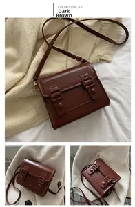 Détails d'un sac bandoulière marron foncé en cuir mat avec sangles à boucle