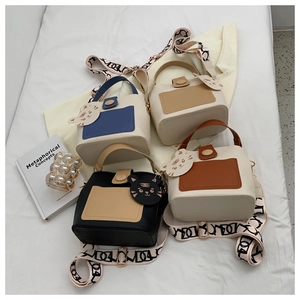 Detail of colorful mini bucket bags with wide jacquard straps and cute cat charms