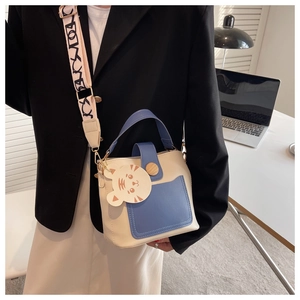 Detail of contrast color crossbody bag with wood button and cartoon tiger charm