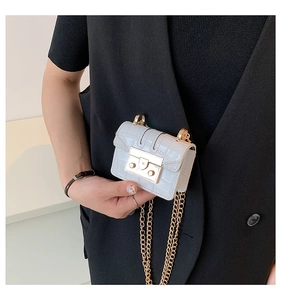 Détail du mini sac à chaîne bleu clair à motif crocodile tenu par un modèle