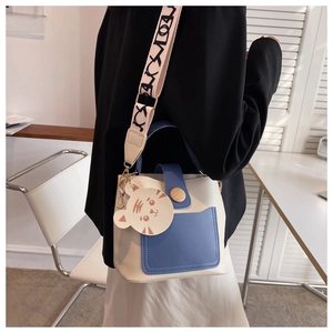 Detail of contrast color crossbody bag with tiger charm and wide printed strap