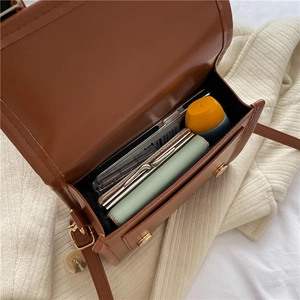 Vue de dessus d'un sac bandoulière en cuir marron montrant sa capacité et son rangement