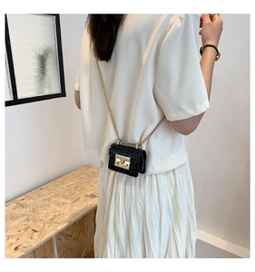 Mini sac noir embossé crocodile avec chaîne dorée porté par un mannequin de dos