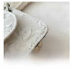 Detail shot of the precise black stitching and 3D floral embroidery on white fabric