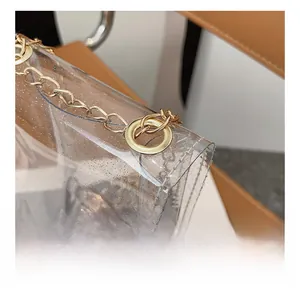 Detail of transparent glitter PVC bag with gold metal hardware and chain strap
