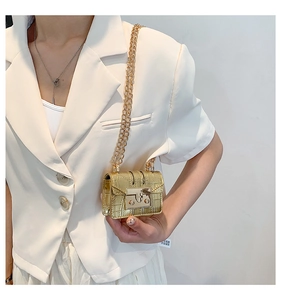Mini sac bandoulière doré avec motif crocodile et chaîne porté par un mannequin