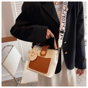 Detail view of contrast color crossbody bag with wide logo strap and tiger charm
