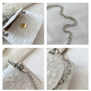 Detail of white textured fabric handbag with 3D floral patterns and silver chain strap