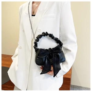 Detail of black cloud bag with satin bow decoration and metallic silver chain strap
