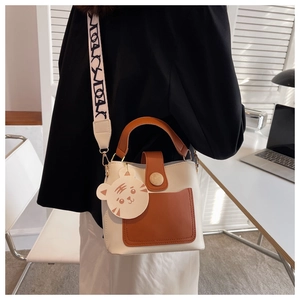 Detail of the contrast bucket bag featuring a wide jacquard strap and cute tiger charm