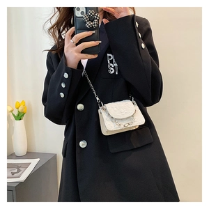 Detailed shot of white mini crossbody bag with floral texture and metal chain straps