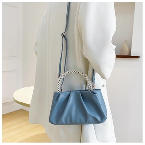 Détail du sac nuage plissé bleu clair avec une élégante poignée en perles