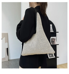 Detail showing the creamy woven texture and sleek black leather strap of the beach bag