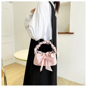 Close-up of pink shoulder bag featuring a large chiffon bow and silver chain strap