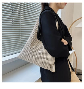 Detail of off-white woven tote bag with honeycomb texture and black leather shoulder strap