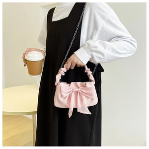 Detailed view of a pink bow handbag featuring a gathered cloud handle and silver chain
