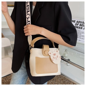 Detail view of contrast color crossbody bag with wide logo strap and tiger charm