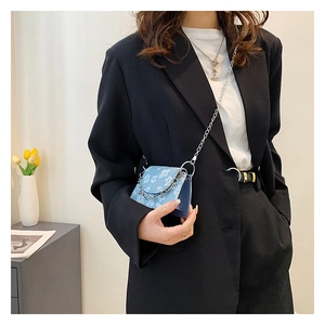 Detail of light blue floral fabric mini crossbody bag with silver chain strap and metal ring