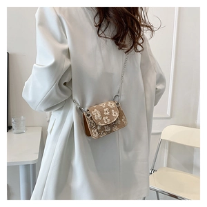 Macro view of khaki mini crossbody bag with 3D floral texture and silver chain strap
