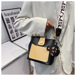 Detail of color-block bucket bag with wide woven strap and cartoon cat charm
