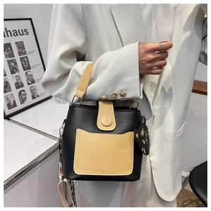 Detail of color-block bucket bag with wide letter-strap and cute cat charm pendant