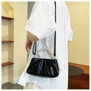 Détail du sac nuage noir avec poignée en perles et texture plissée sur chemise blanche