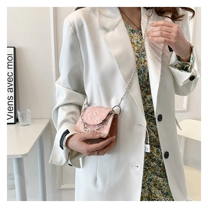 Model wearing a light pink mini crossbody bag with embossed floral texture and silver chain