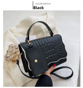 Detail of black faux crocodile texture handbag with gold metal hardware and mini pouch