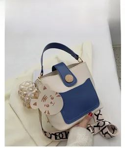 Detail view of cream bucket bag with blue pocket and stylish patterned wide strap