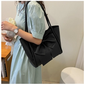 Détail du sac cabas noir élégant avec un grand nœud et de longues bretelles fines
