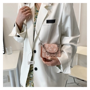 Detailed view of mini pink crossbody bag with white lace floral pattern and silver chain