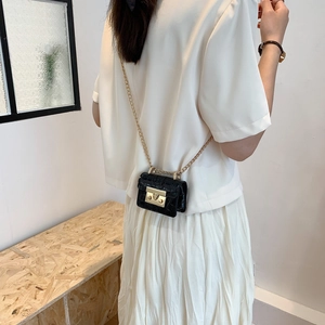 Mini sac à bandoulière noir à motif crocodile avec chaîne dorée porté par un modèle