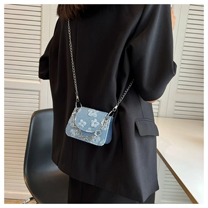 Blue denim mini bag with 3D floral texture and silver chain strap on model