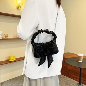 Fashionable black crossbody bag with large bow and scrunchie handle on model