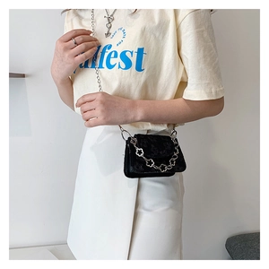 Detail of a black embossed crossbody bag with dual silver chains on a model