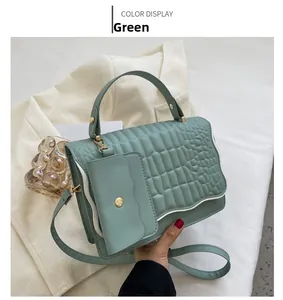 Detail of green pleated crossbody bag with gold hardware and mini pouch charm