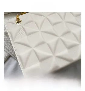 Détail du sac cabas blanc avec texture gaufrée géométrique en 3D et chaîne dorée