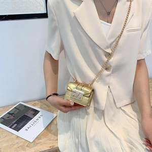 Mini sac doré à motif crocodile avec bandoulière chaîne porté par un mannequin chic